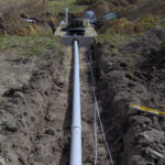 View of the sewer going to the home and the wires that provide electric to the system. Wires will be enclosed in a chase pipe to prevent damage where necessary.