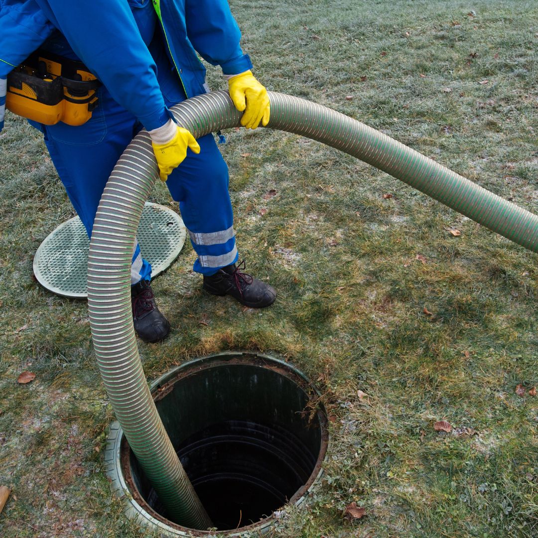 An image of a man sticking a hose into a sewer system.