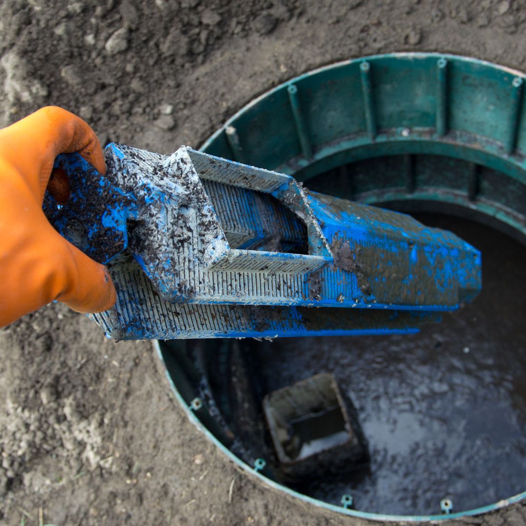 An image of someone pulling a dirty filter out of a septic system.