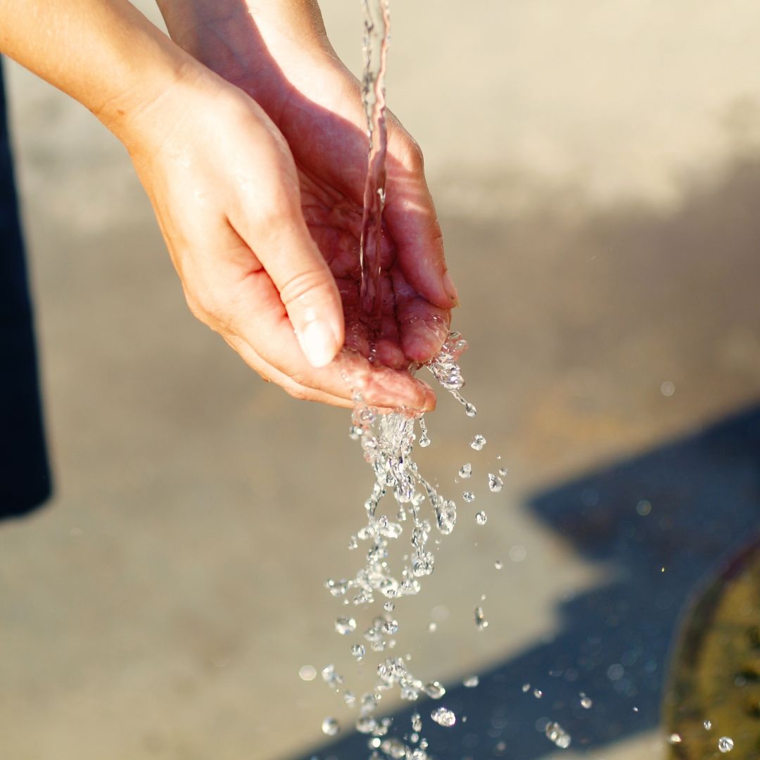 Hands through running water